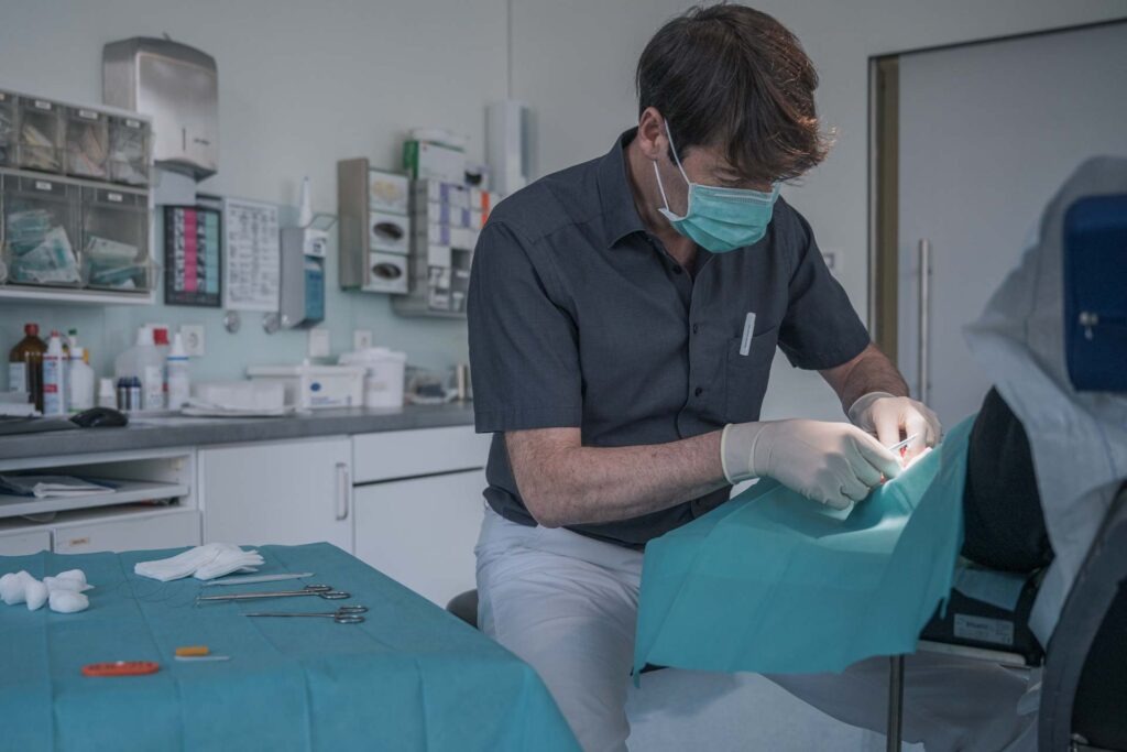Dr. Martin Hillmers im Behandlungszimmer an einem steril abgedeckten Patienten