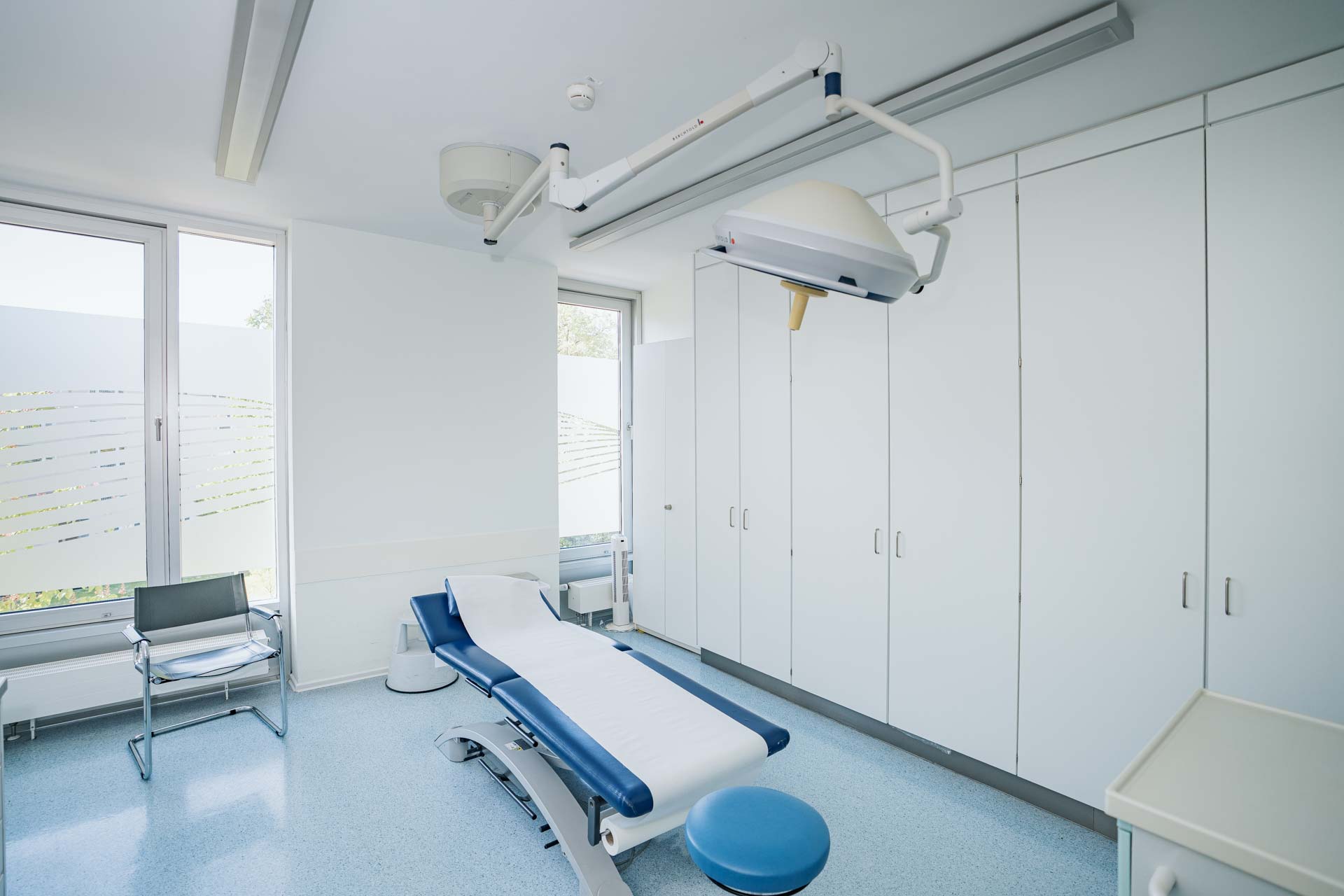 Blick in ein Behandlungszimmer mit Patientenliege und schwenkbarer Deckenlampe